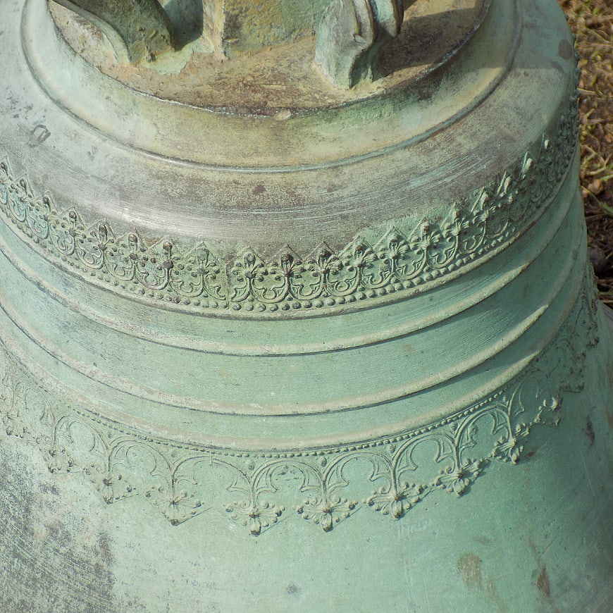 Close-up of weathered green patina church bell with ornate details
