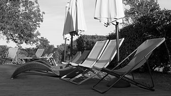 Black and white deck chairs and umbrellas on wooden terrace