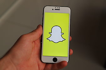Hand Holding White Smartphone Displaying Snapchat App Icon