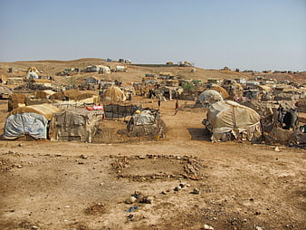 Wide view of refugee camp with makeshift tents on dry hills