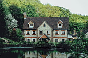 Charming brick house by a river with lush green trees