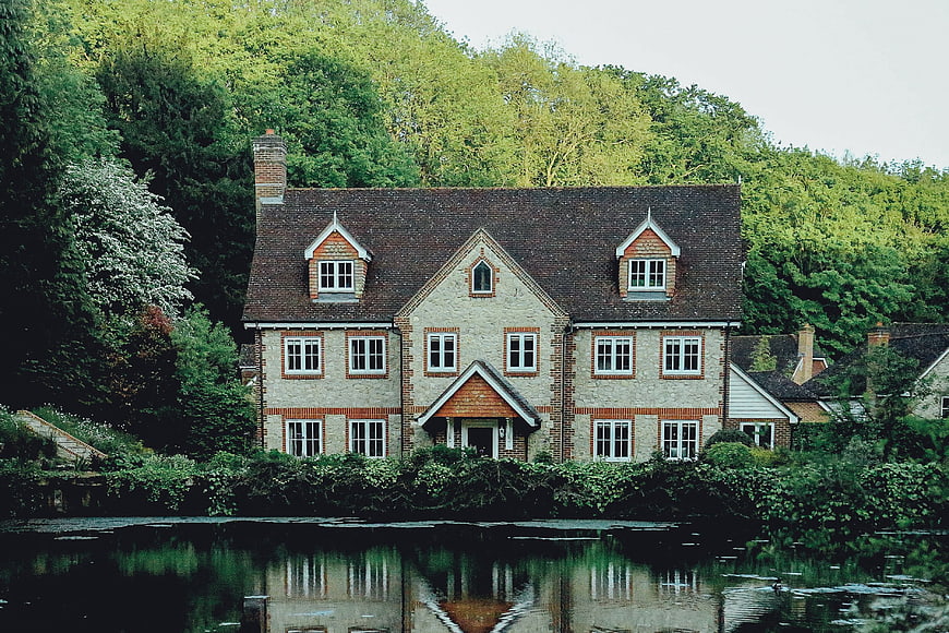 Charming brick house by a river with lush green trees