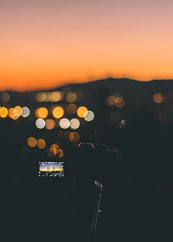 Camera capturing city bokeh at sunset