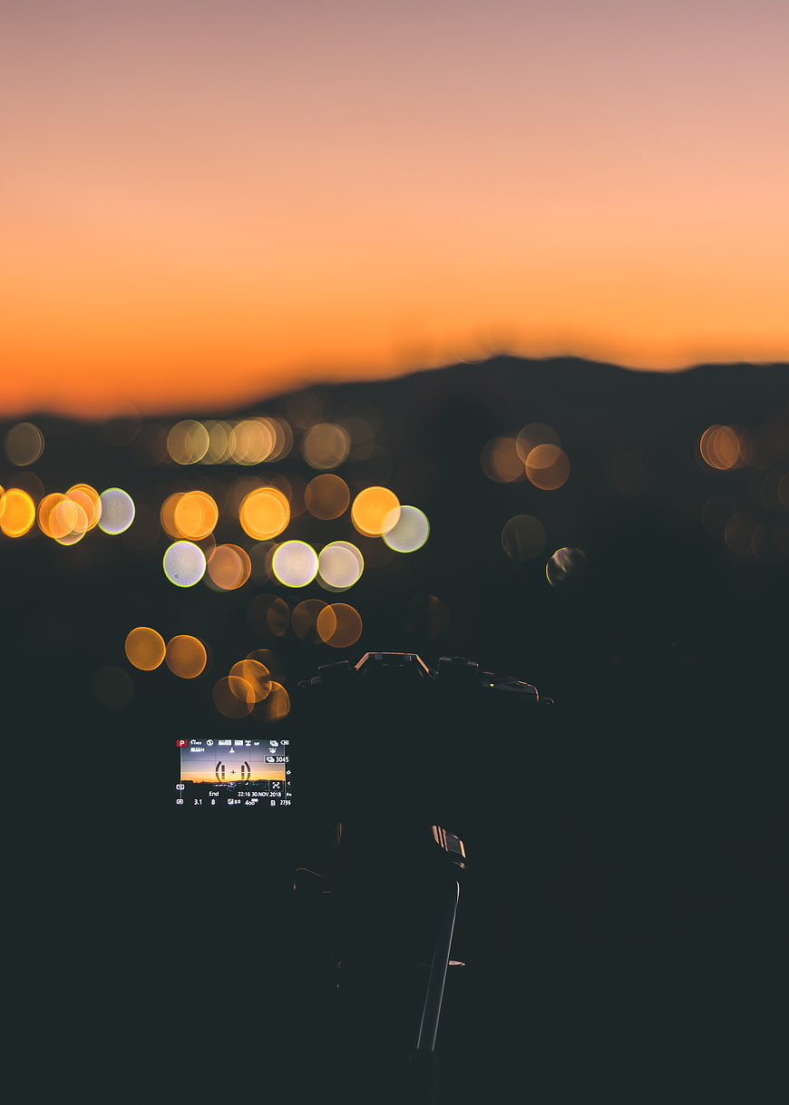 Camera capturing city bokeh at sunset