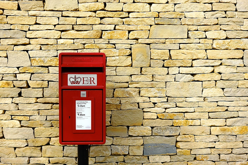 Red Royal Mail Post Box Against Stone Wall