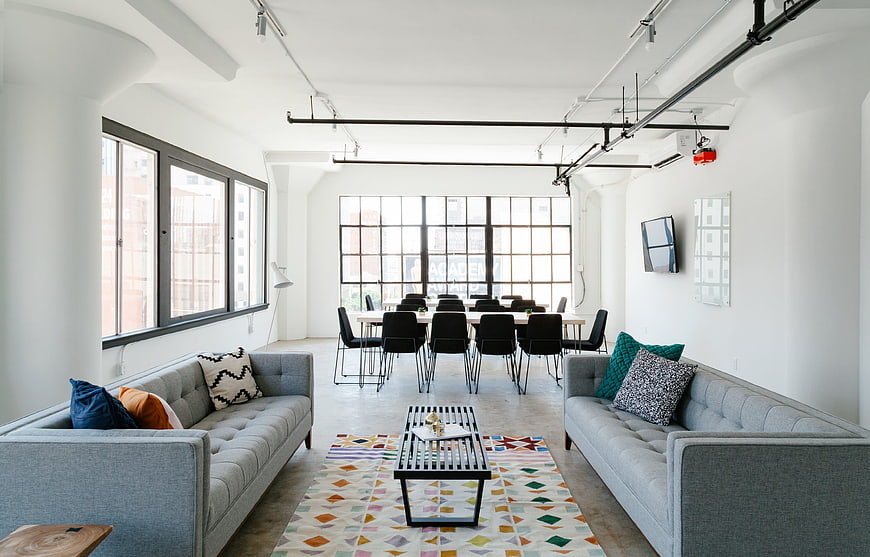 Modern industrial office lounge with gray sofas and conference table