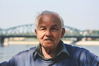 Portrait of elderly man outdoors with bridge background