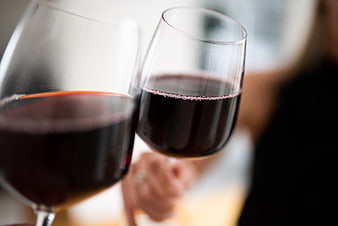 Close-up of two red wine glasses clinking in a toast