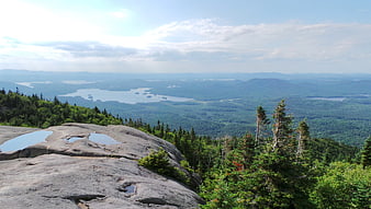 Panoramic mountain landscape with rocky outcrop and distant lake