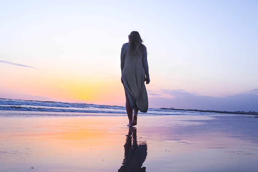 Woman Walking on Beach at Sunset with Reflection