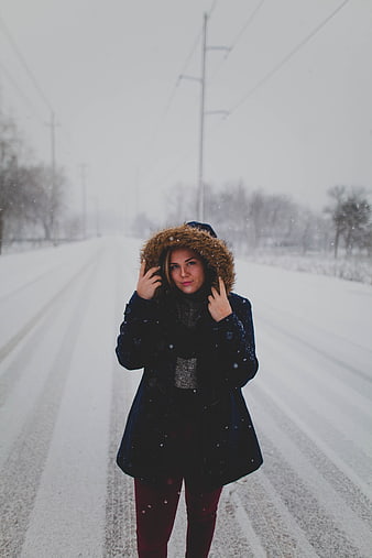 Woman in winter coat standing on snowy road