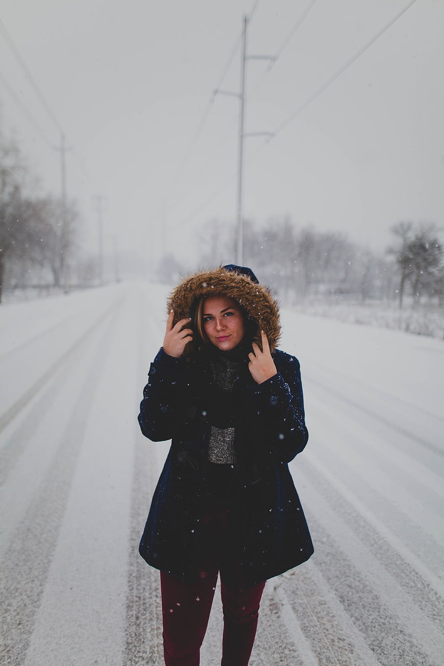 Woman in winter coat standing on snowy road