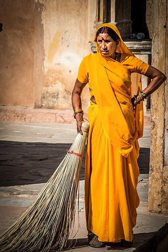 Indian woman in yellow sari holding broom