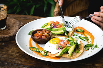 Healthy breakfast tacos with avocado and eggs on wooden table