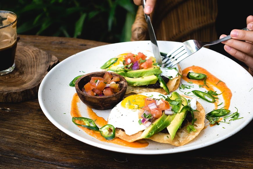Healthy breakfast tacos with avocado and eggs on wooden table