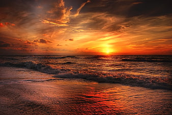 Dramatic Orange Sunset Over Ocean Waves and Beach