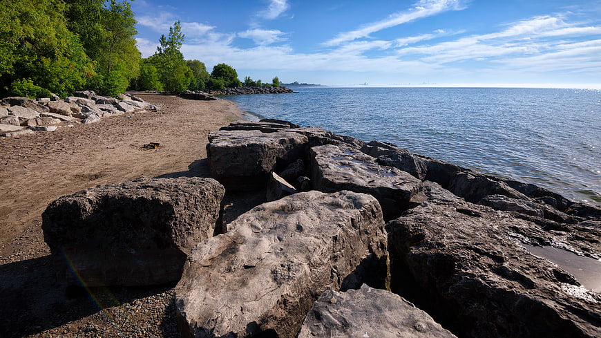 Rocky shoreline with sandy beach and blue lake water