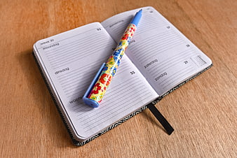 Open Weekly Planner Notebook With Colorful Pen On Wooden Desk