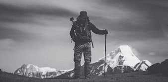 Hiker with Backpack and Poles Facing Snowy Mountain Peak