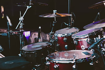 Red drum kit on stage with microphones and cymbals