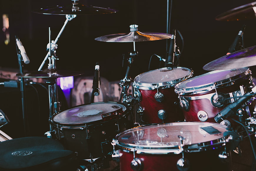 Red drum kit on stage with microphones and cymbals