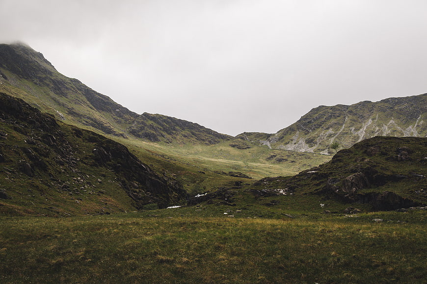 Misty Mountain Valley with Green Grass and Overcast Sky