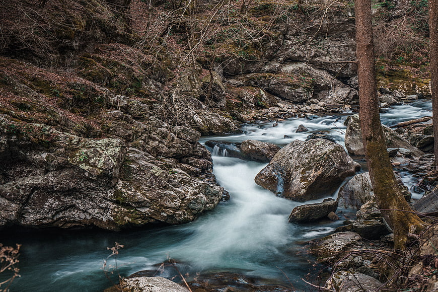 Long exposure stream flowing through rocky forest landscape