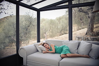 Woman Sleeping on Sofa in Glass Sunroom