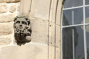 Ancient stone face sculpture on historic church wall