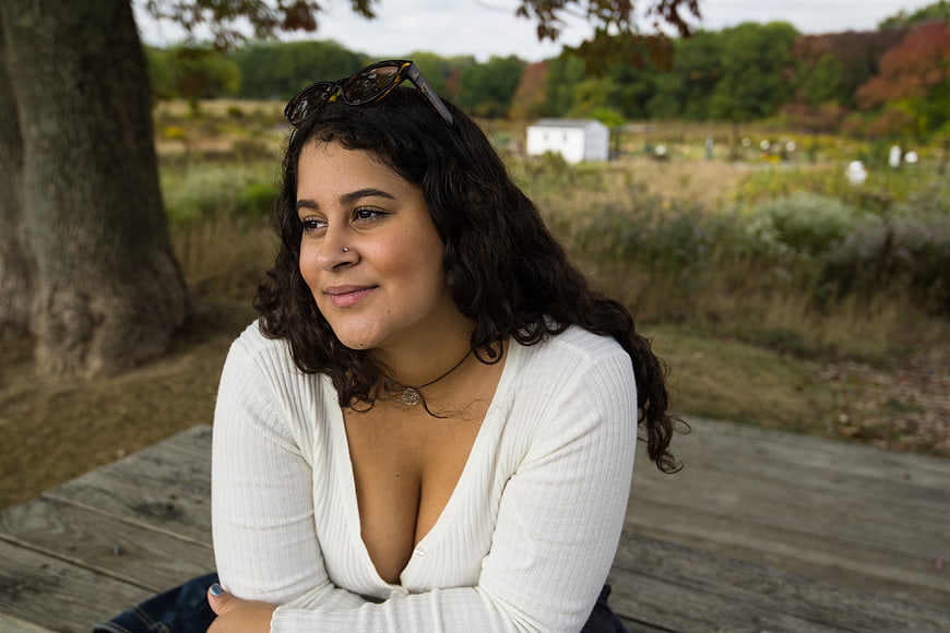 Smiling Brunette Woman Sitting on Wooden Deck in Park