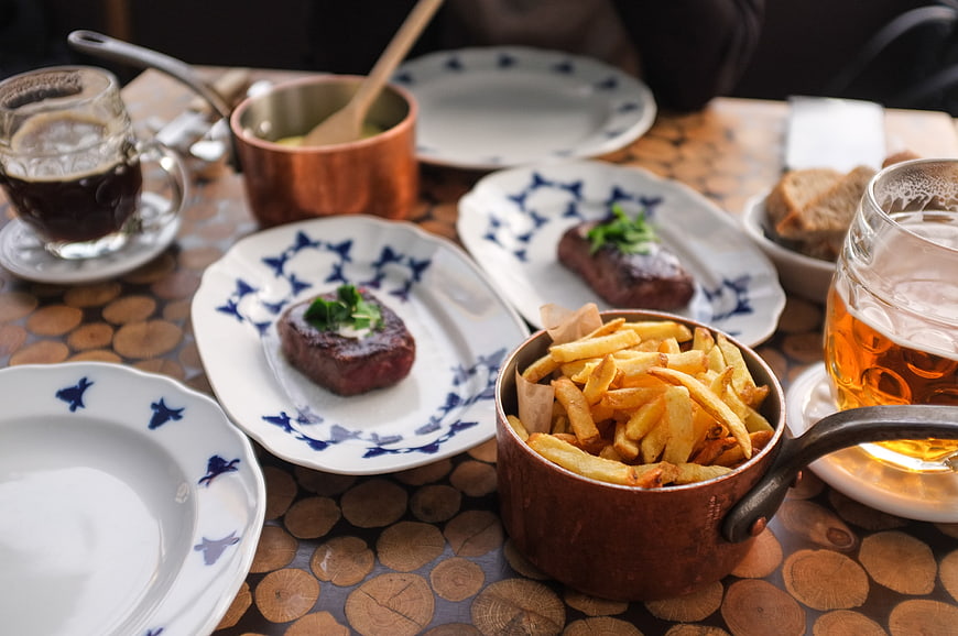 Steak and fries dinner with beer on rustic wooden table