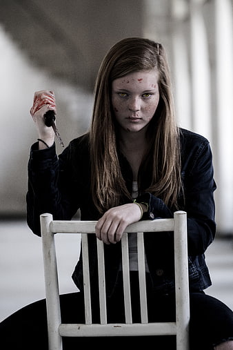 Young woman with glowing yellow eyes holding bloody knife