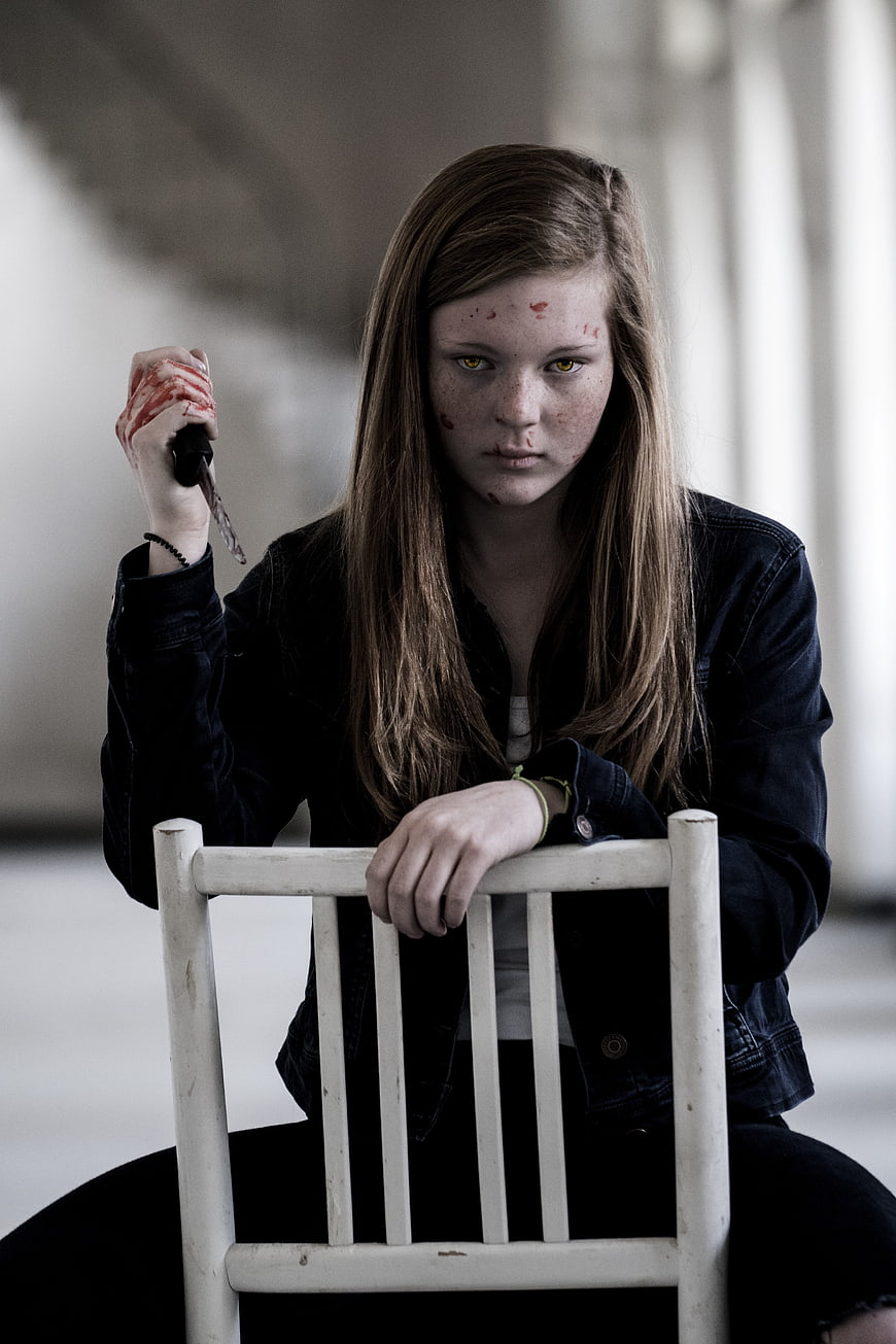 Young woman with glowing yellow eyes holding bloody knife