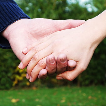 Close-up of two hands holding each other outdoors