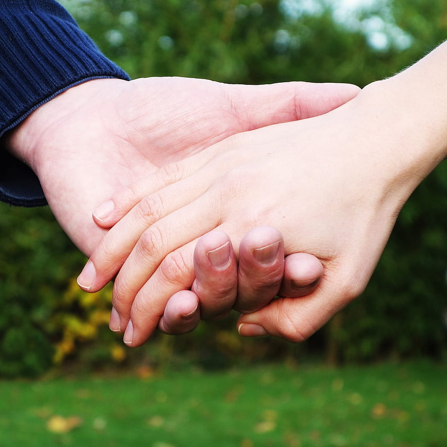 Close-up of two hands holding each other outdoors