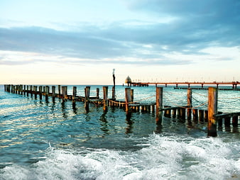 Woman standing on wooden pier with crashing waves