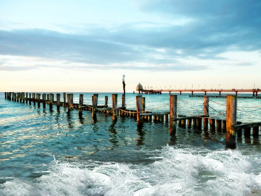 Woman standing on wooden pier with crashing waves