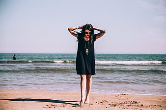 Woman with Tattoos Standing on Sandy Beach