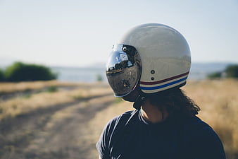Man in Vintage Motorcycle Helmet Looking Out at Scenic Landscape