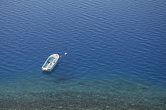 Aerial view of a small white boat floating on deep blue sea
