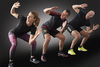 Three Athletes Performing Dynamic Fitness Exercise On Dark Background