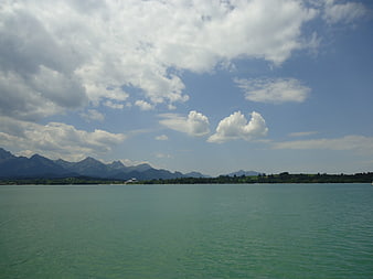 Serene turquoise lake with distant mountains and blue sky