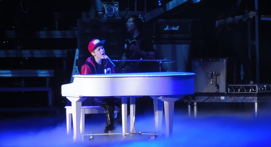 Justin Bieber performing at white piano on stage