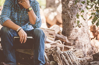 Man in Plaid Shirt Sitting in Forest with Notebook
