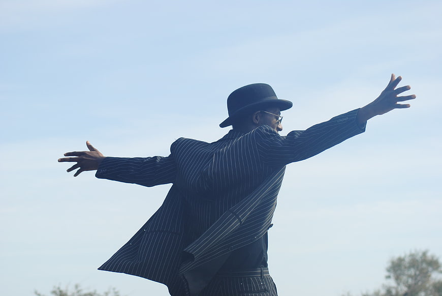 Man in Pinstripe Suit and Bowler Hat with Arms Outstretched