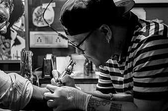 Tattoo artist concentrating on inking a client's arm