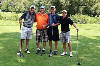 Group of four men golfers posing on a sunny golf course