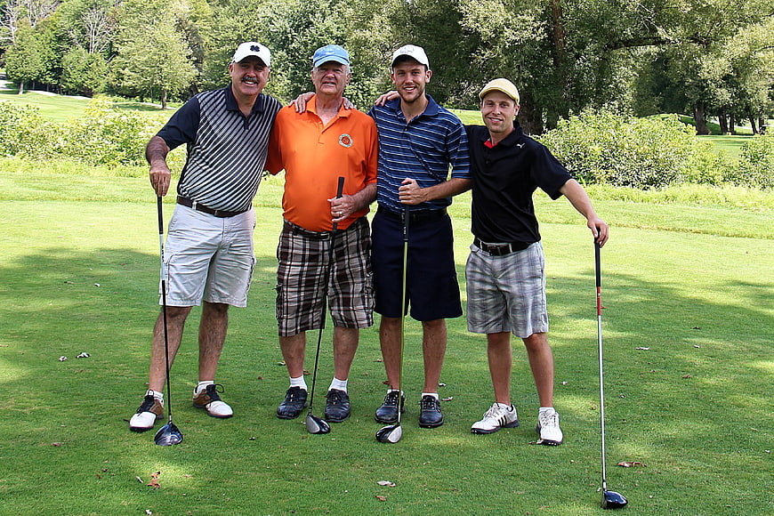 Group of four men golfers posing on a sunny golf course