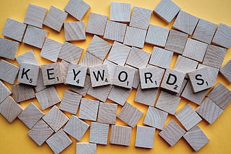 Wooden Scrabble Tiles Spelling Keywords on Yellow Background
