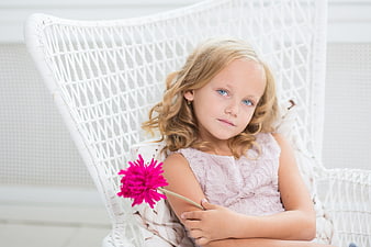 Cute blonde girl with blue eyes holding pink flower
